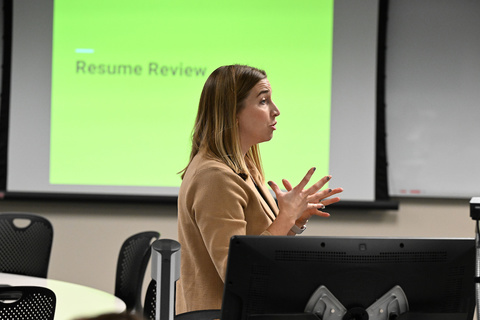 Woman addressing classroom with power point presentation behind her