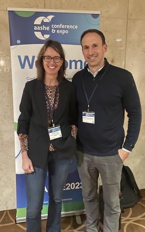 Cornelia Lang and Stratis Giannakouros stand in front of a banner that says "aashe conference and expo"