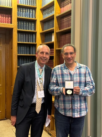 Claudio Margulis, chemistry professor, holding a silver medal next to Royal Society of Chemistry president.