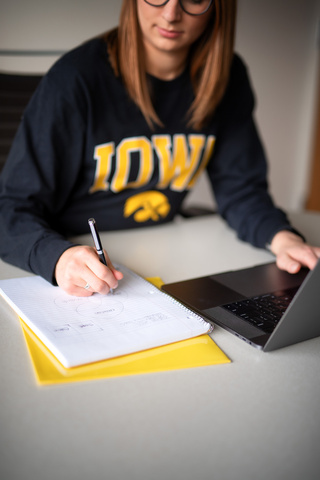 A student takes notes and studies on a laptop